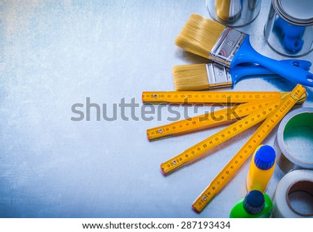 Paint tools with duct tapes and wooden meter on metallic background construction concept.