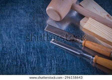 Lump hammer wooden studs and flat chisels on scratched metallic background construction concept.