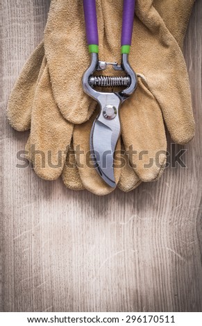 Close up view of sharp pruning shears and working leather safety gloves on wooden board agriculture concept.
