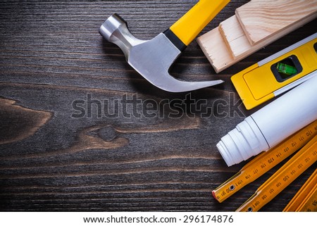 Construction level rolled up blueprint claw hammer wooden meter and bricks on vintage wood surface maintenance concept.