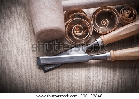 Wooden mallet scobs firmer chisels on wood surface horizontal view construction concept.