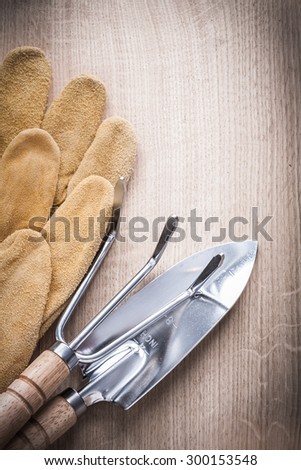 Gardening trowel fork with shovel and leather safety gloves on wooden background vertical version agriculture concept.