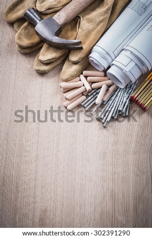 Wooden meter dowels construction plans claw hammer leather protective gloves and metal nails on wood board maintenance concept.