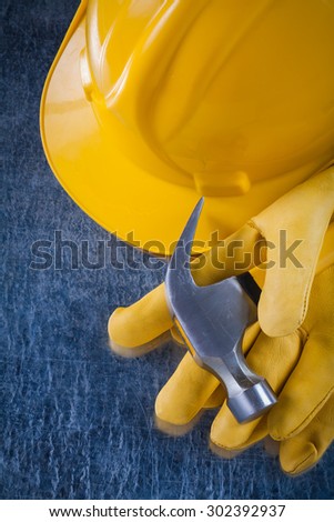 Pair of safety gloves building helmet and claw hammer on scratched metallic background construction concept.