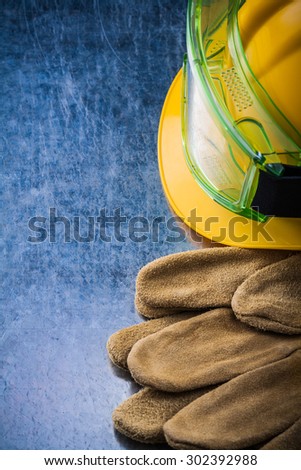 Set of brown construction leather gloves building helmet and plastic protective glasses on scratched metallic background maintenance concept.