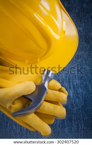 Leather safety gloves building helmet and claw hammer on scratched metallic surface construction concept.