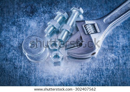 Metal adjustable wrench bolt washers screw-nuts and screwbolts on scratched metallic background construction concept.