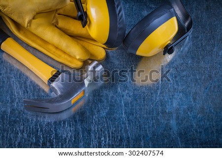 Noise insulation earmuffs claw hammer and leather protective gloves on metallic background construction concept.