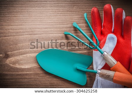 Safety gloves hand spade and rake on wooden background.