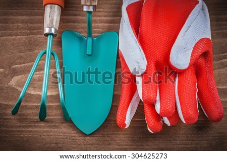 Protective gloves hand spade and rake on wood board.