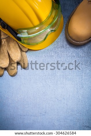 Copy space of waterproof boots protective leather gloves building helmet and safety glasses on scratched metallic background construction concept.