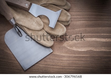 Surfacer bricklaying trowel and leather construction gloves on wood board.