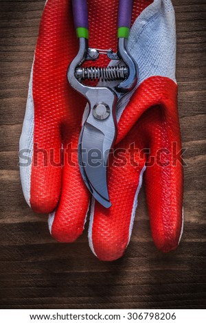 Gardening working glove and steel secateurs on wooden background.