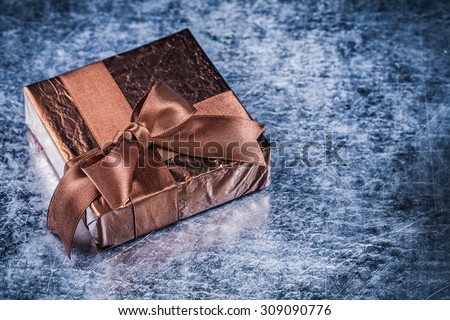 Packed present with tied bow on metallic background holiday concept.
