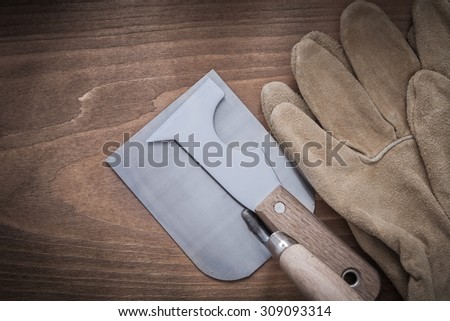 Sharp paint scraper bricklaying trowel and leather safety gloves.