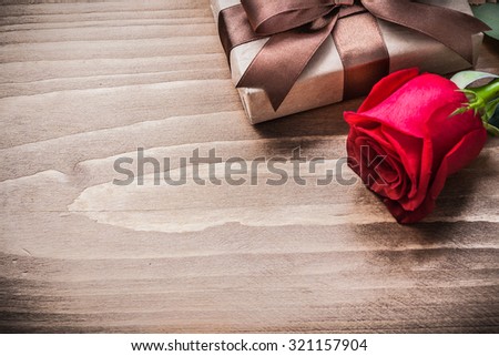 Boxed present expanded rose head on wooden board holiday concept.