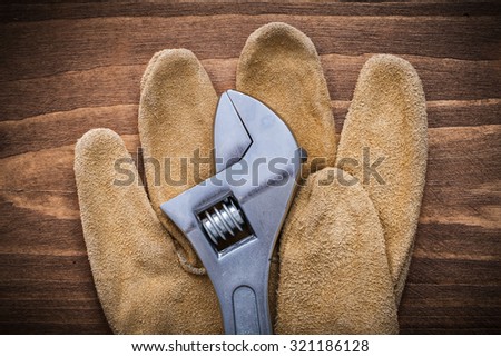 Adjustable spanner leather protective gloves on wooden board construction concept.