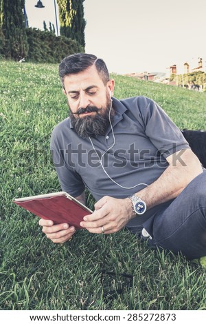 Adult hipster fashion man with digital tablet relaxing at the park - Concept of new trends and technology mixed with vintage lifestyle - Business man on retro nostalgic filtered look
