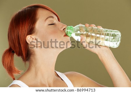young red haired woman is drinking mineral water