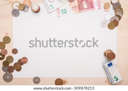 Different coins from different countries arranged around a white piece of paper.