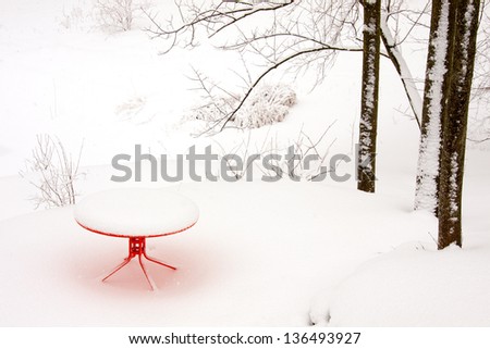snow covered orange table in a snowy landscape with snow falling