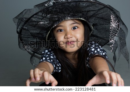 Portrait of little Asian girl in black hat and black clothing