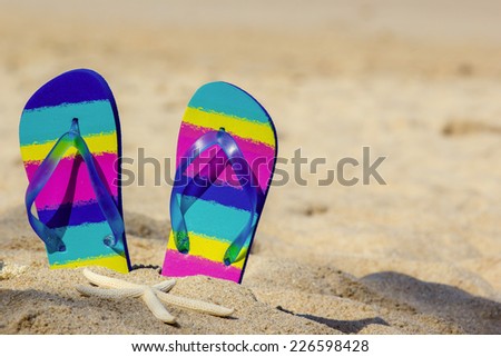 Colorful flip-flops on sand beach