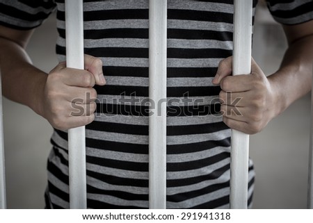 Hands of the Asian prisoner behind the jail