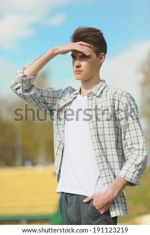 Young man looking into the distance on a hot sunny summer windy day outdoors, blue sky