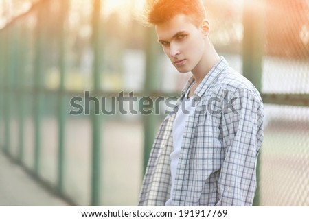 Fashion portrait handsome man in summer sunny day, strong look on camera, street fashion, hip-hop