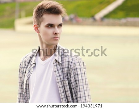 Outdoor summer portrait handsome man in plaid shirt with stylish hairstyle looking away