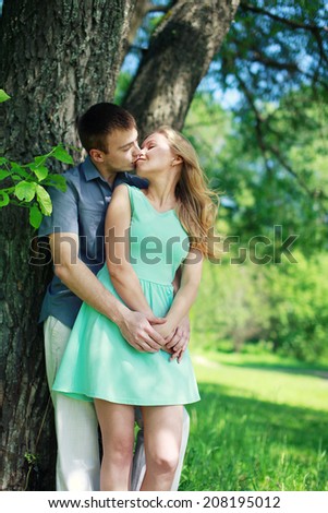 Lovely sensual couple in love enjoying kiss outdoors in warm summer day in the city park