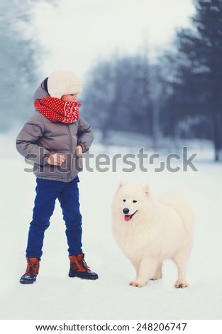 Winter and people concept - boy with white Samoyed dog outdoors in winter day