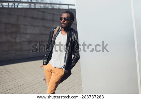 Street fashion concept - handsome stylish african man standing in the city against a metal wall