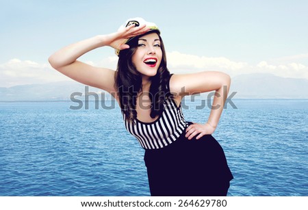Travel, cruise, tourism and people concept - pretty smiling sailor woman saluting against the sea