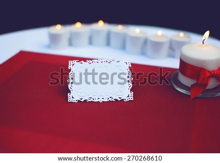 Paper card for a text on decorated table with burning candles. Wedding, banquet, holiday background - concept