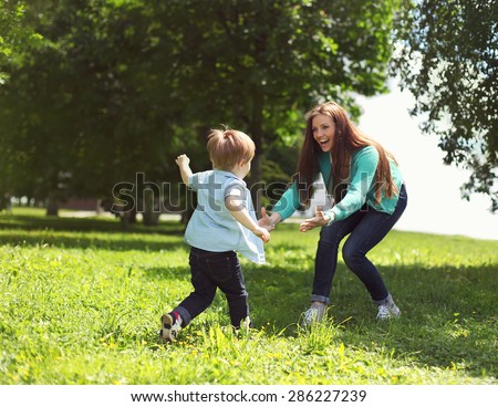Life moment of happy family! Mother and son child playing having fun together on the grass in sunny summer day