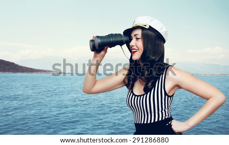 Travel, cruise, tourism and adventure concept - pretty smiling woman of a sailor looking through binoculars against the sea and island