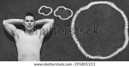 Sport, fitness and healthy lifestyle concept - handsome confident sportsman relaxing and thinking on the ground with painted clouds, top view