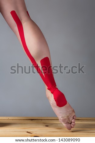 Red strapping on an injured calf of a young adult female dancer.