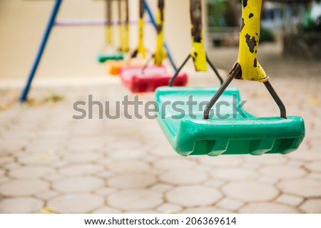 Colorful swings and rusty iron chain on cement block floor background