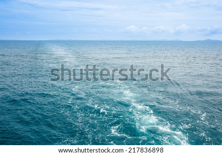 Foamy track of big ship on blue sea and sea gull flying