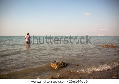 The big man standing on the beach fishing in the ocean