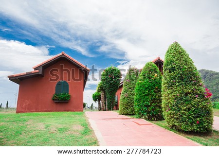 Little cray house with green garden in cloudy day
