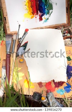 Textured paper on palette lying on painterÃ¢Â?Â?s case on the grass