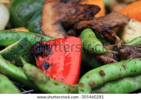 Fresh mixed vegetables being cooked on a cast iron grill and basket with seasonings and char marks with string beans, red peppers, mushrooms and zucchini