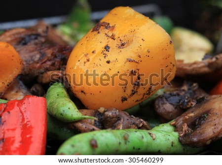 Fresh mixed vegetables being cooked on a cast iron grill and basket with seasonings and char marks with yellow bell pepper