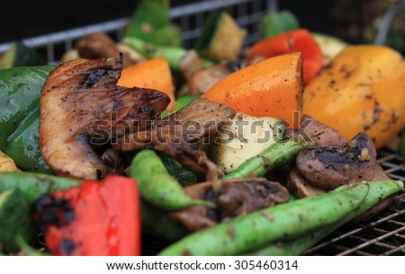 Fresh mixed vegetables being cooked on a cast iron grill and basket with seasonings and char marks