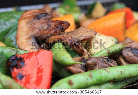 Fresh mixed vegetables being cooked on a cast iron grill and basket with seasonings and char marks with string beans, peppers, mushrooms and zucchini