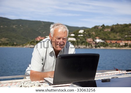 The senior man using the laptop on the sailboat.